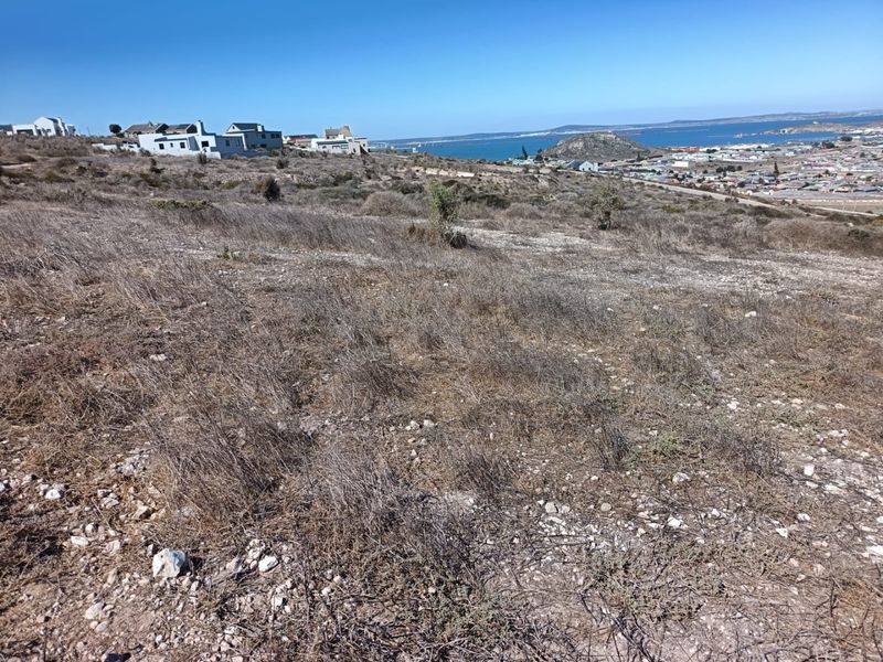 A view of the vacant residential land featuring a natural sloped landscape with distant coastal and town views.