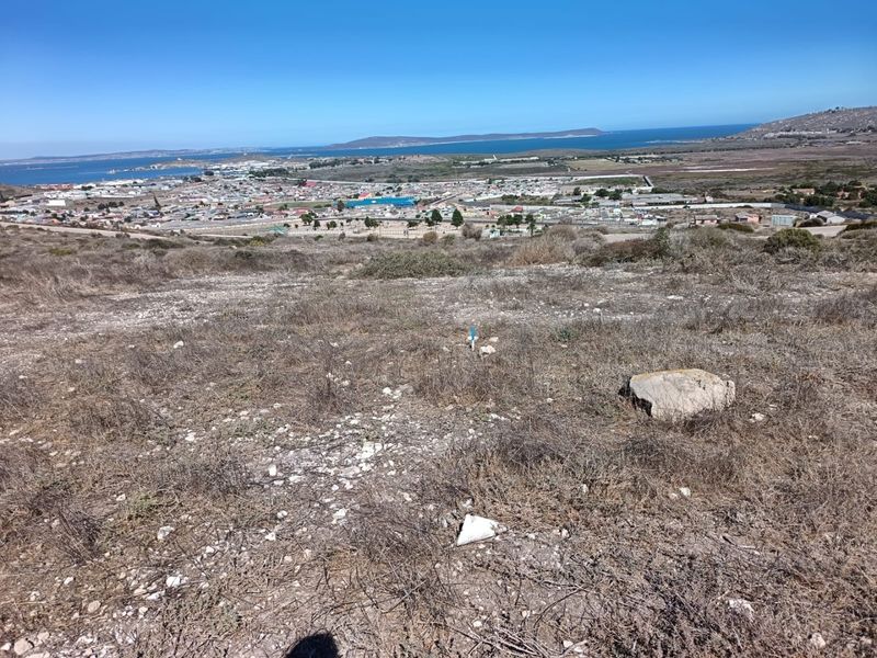 An elevated view overlooking a coastal town and bay, showcasing the natural landscape and surrounding area from the vacant residential plot.