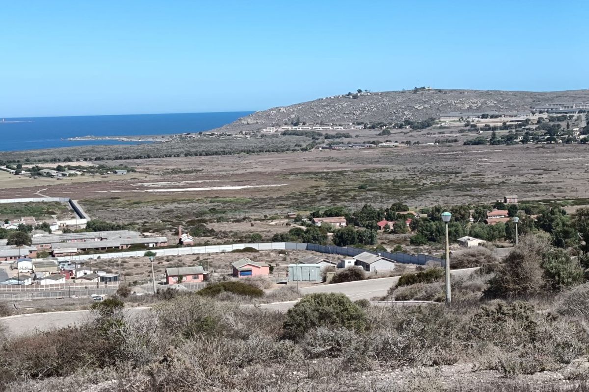 A wide-angle view of the coastal landscape and surrounding residential area, showcasing the natural terrain and proximity to the ocean.