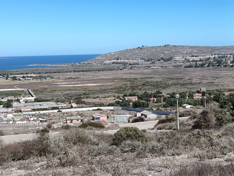 A wide-angle view of the coastal landscape and surrounding residential area, showcasing the natural terrain and proximity to the ocean.