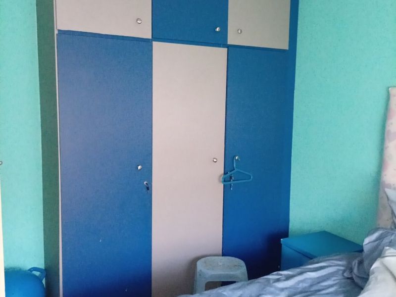 A bedroom featuring a large built-in wardrobe with blue and grey cabinetry and recessed ceiling lighting.