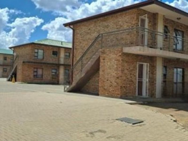 Exterior view of a multi-story apartment complex featuring face brick construction, external staircases, and paved common areas.