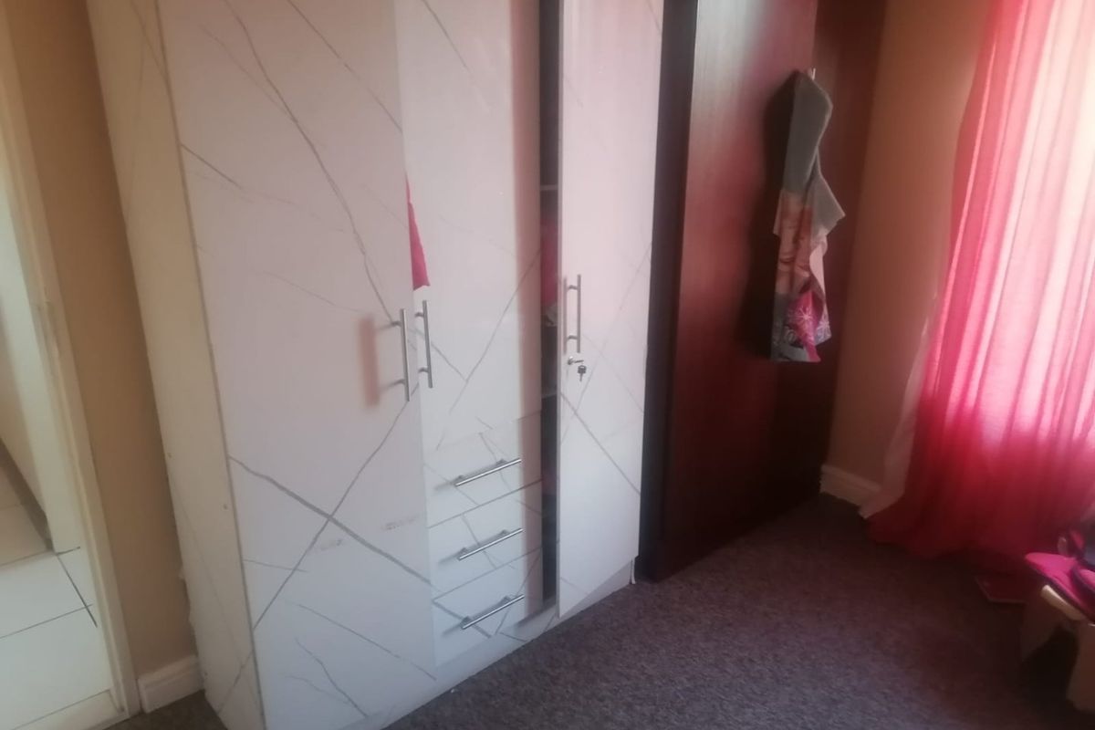 A bedroom featuring a modern built-in wardrobe with marble-effect finish and integrated drawers.