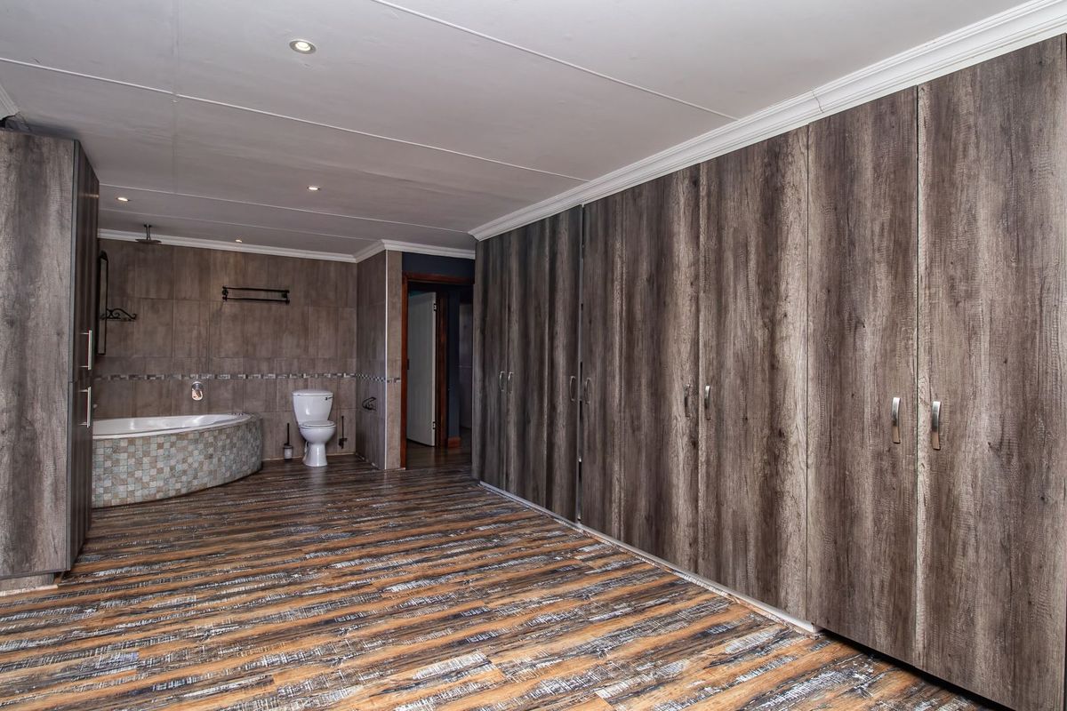 Spacious bedroom featuring extensive built-in cabinetry, recessed lighting, and an integrated en-suite bathroom area with a corner bathtub and toilet.