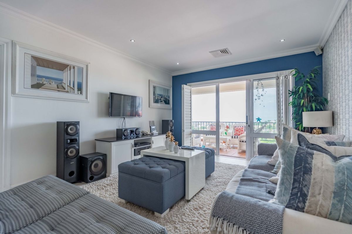 A bright and well-maintained living room featuring recessed lighting, crown molding, and direct access to a private balcony through sliding glass doors.