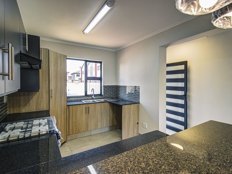 Modern kitchen featuring wood-finish cabinetry, granite countertops, subway tile backsplash, and a functional layout with a breakfast bar.