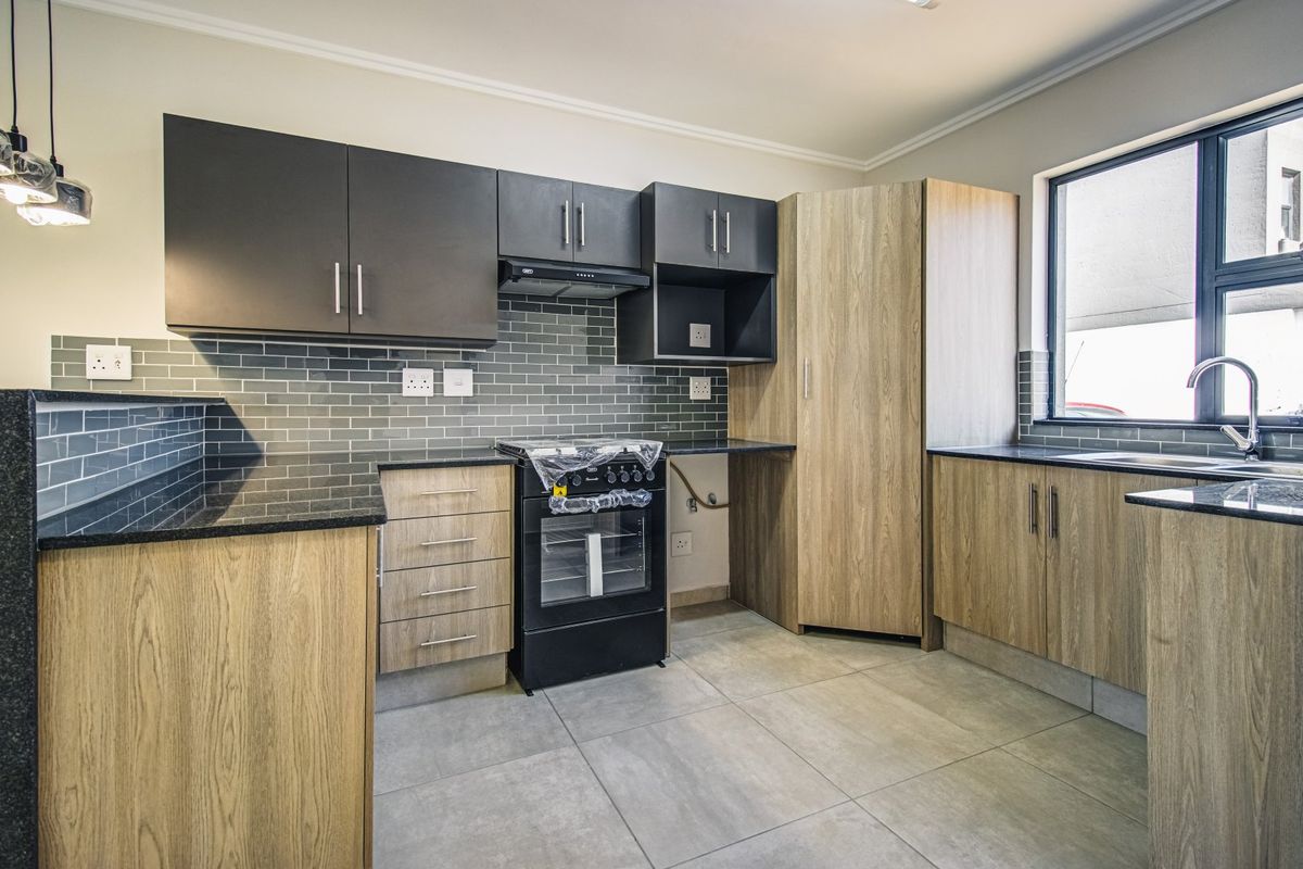 Modern kitchen featuring wood-grain and dark cabinetry, granite countertops, subway tile backsplash, and built-in oven with extractor fan.