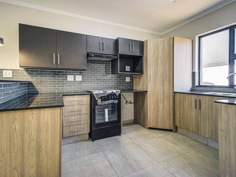 Modern kitchen featuring wood-grain and dark cabinetry, granite countertops, subway tile backsplash, and built-in oven with extractor fan.
