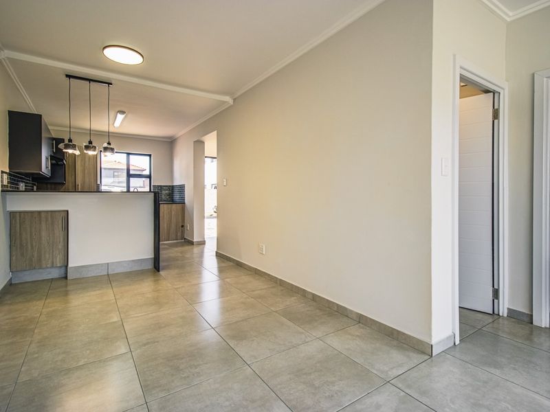 An open-plan living and kitchen area featuring modern tiled flooring, contemporary cabinetry, and clean finishes, providing a versatile and bright space.