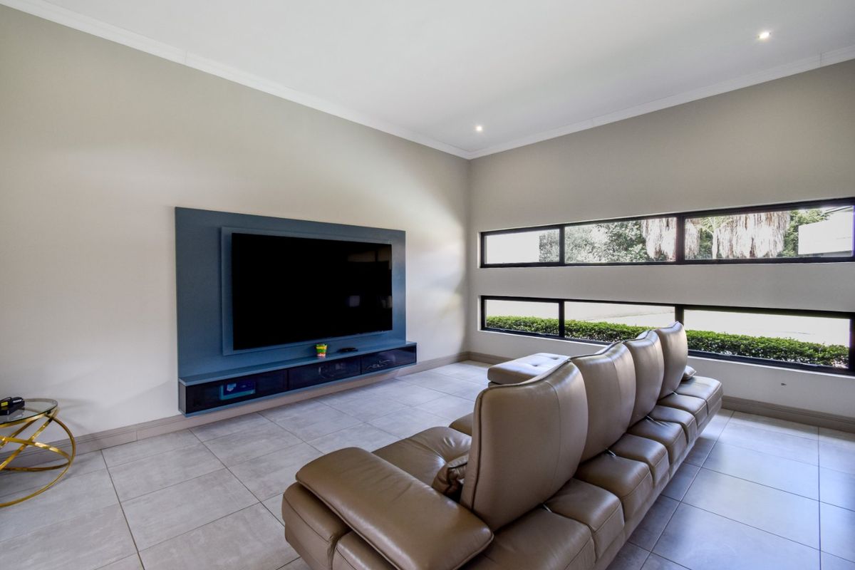 A modern living room featuring tiled flooring, a built-in media console, and horizontal windows providing natural light.