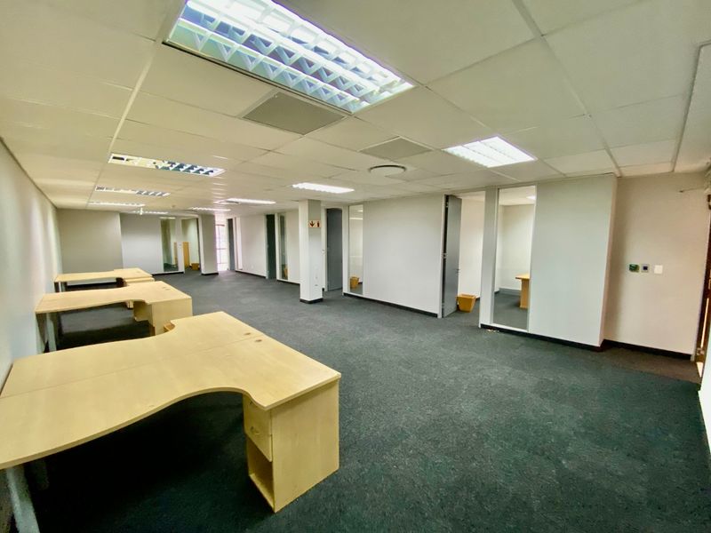Open-plan commercial office space featuring suspended ceilings, recessed lighting, carpeted flooring, and internal glass partitions for private office areas.