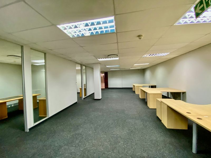 Open plan commercial office space featuring carpeted flooring, suspended ceilings with recessed lighting, and glass-partitioned private offices.