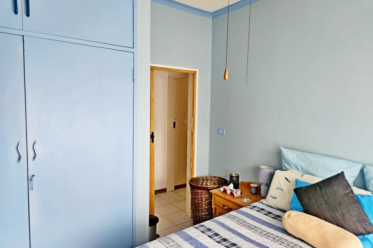 A bedroom featuring light blue walls, coving, and a built-in wardrobe with access to an adjacent hallway.