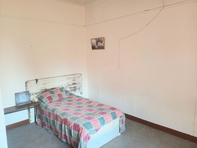 A simple bedroom featuring a picture rail and skirting boards, requiring cosmetic updates to the wall finishes and electrical fixtures.