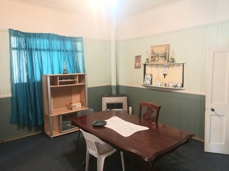 Dining room featuring timber wall paneling, a wood-burning stove, and coved ceilings. The space offers a traditional layout with potential for cosmetic updates.