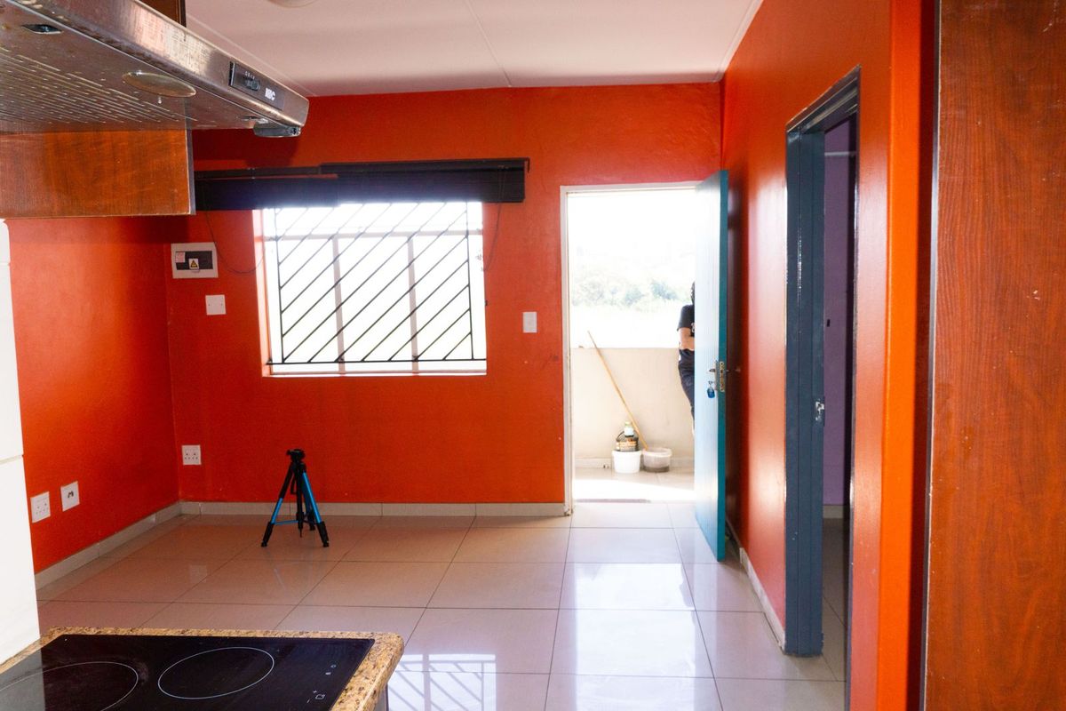 A functional kitchen area featuring tiled flooring, a built-in hob with extractor fan, and direct access to an outdoor balcony space.