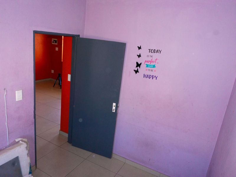 An empty bedroom featuring tiled flooring and a doorway leading to an adjacent room with vibrant red walls.