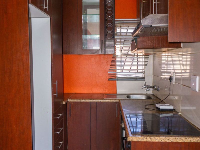 Compact kitchen featuring dark wood cabinetry, granite countertops, integrated hob, and extractor fan, requiring minor ceiling repairs and cosmetic updates.