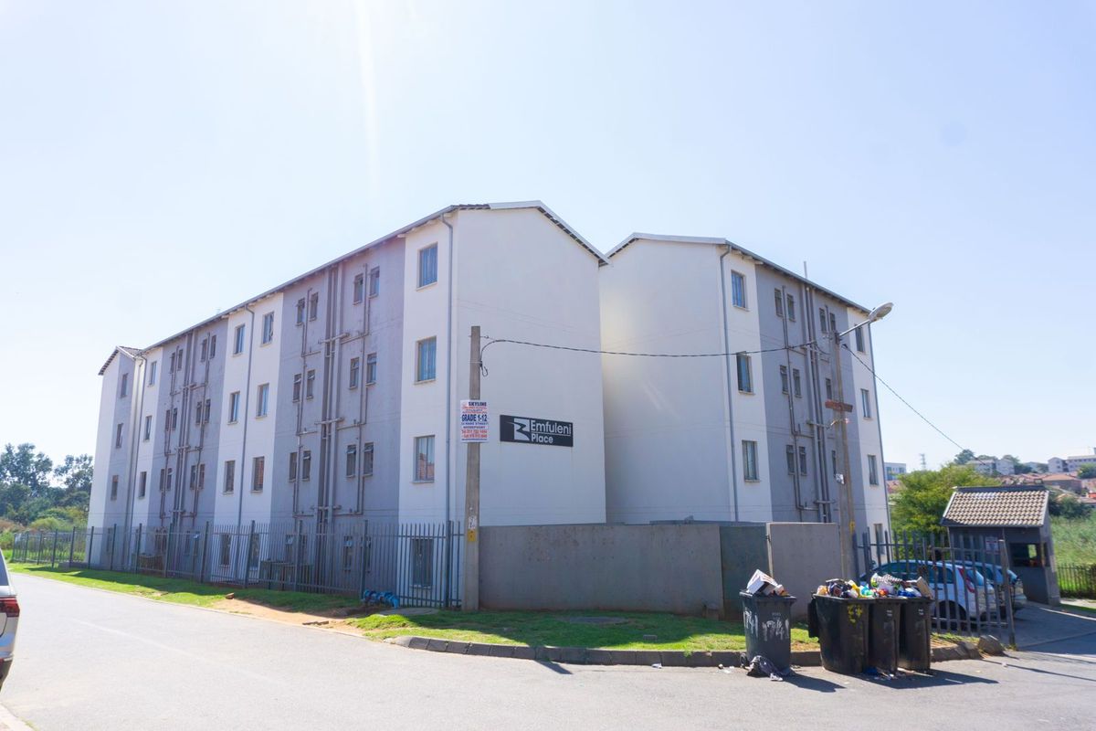 Exterior view of Emfuleni Place apartment complex, featuring multi-story residential blocks with perimeter fencing and paved access.