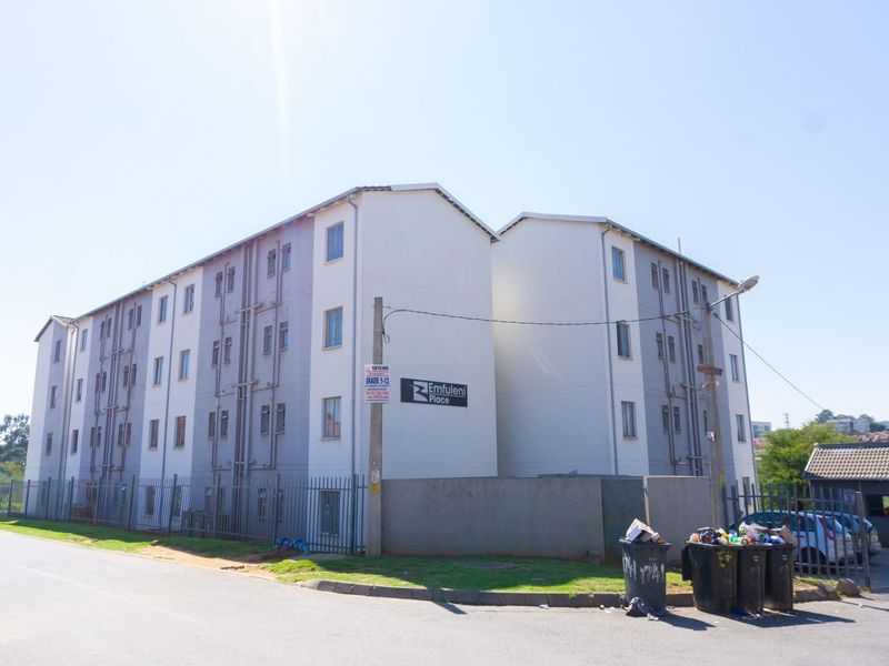 Exterior view of Emfuleni Place apartment complex, featuring multi-story residential blocks with perimeter fencing and paved access.