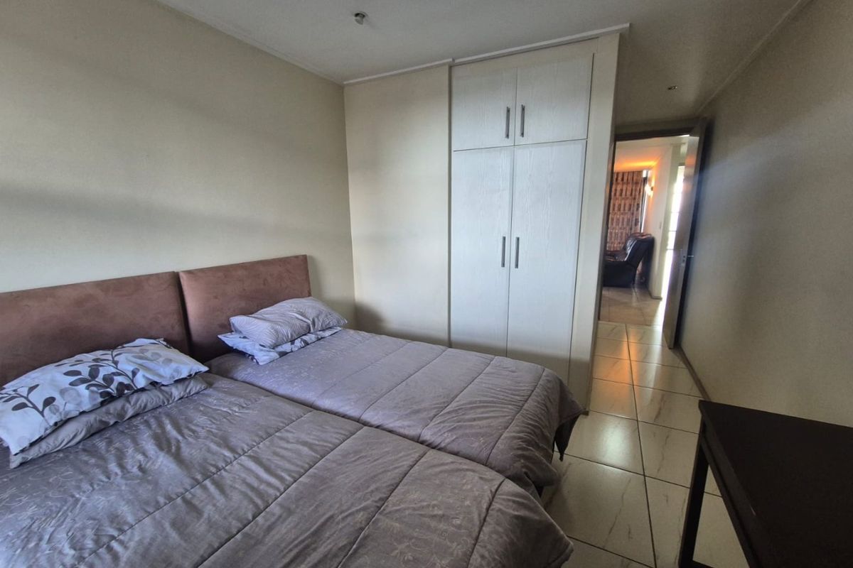 A bedroom featuring tiled flooring and a built-in wardrobe, with direct access to an adjacent living area.