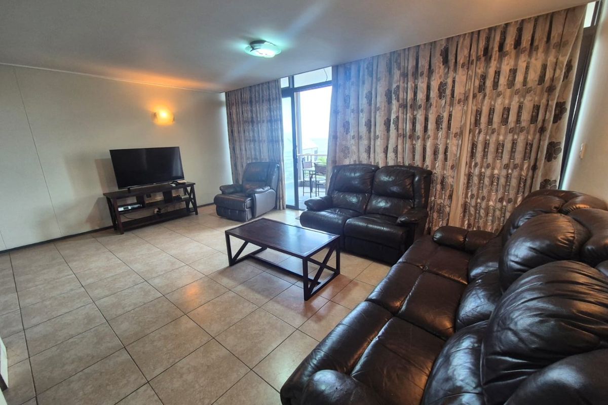 Spacious living room featuring tiled flooring and a sliding glass door providing access to the balcony area.