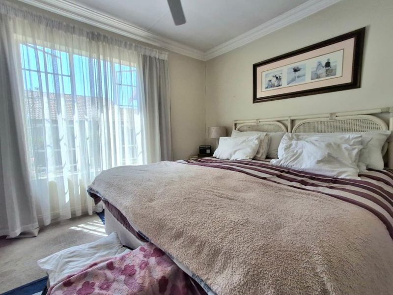 A well-lit bedroom featuring crown molding, a ceiling fan, and a large sliding glass door providing natural light.