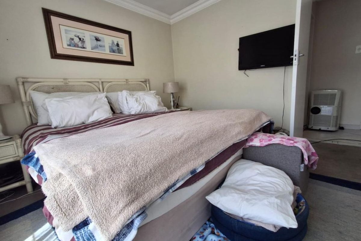 A standard bedroom featuring crown molding and a wall-mounted television, providing a functional sleeping space with neutral wall finishes.