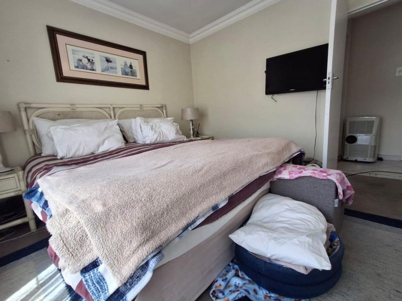 A standard bedroom featuring crown molding and a wall-mounted television, providing a functional sleeping space with neutral wall finishes.