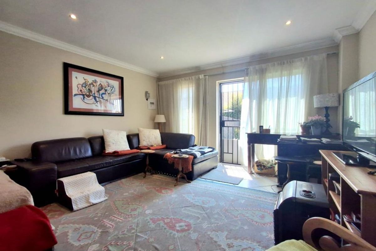 A comfortable living room featuring tiled flooring, recessed downlighting, and direct access to an outdoor area through a secure glass door.