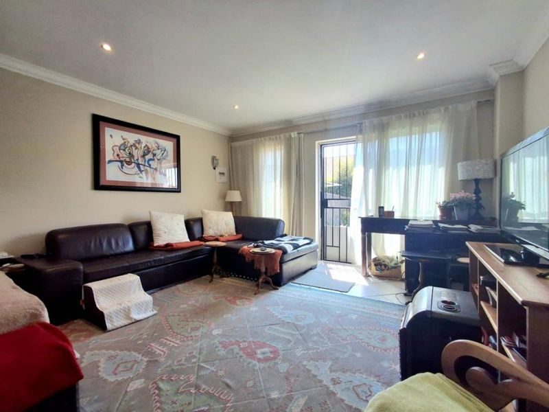 A comfortable living room featuring tiled flooring, recessed downlighting, and direct access to an outdoor area through a secure glass door.