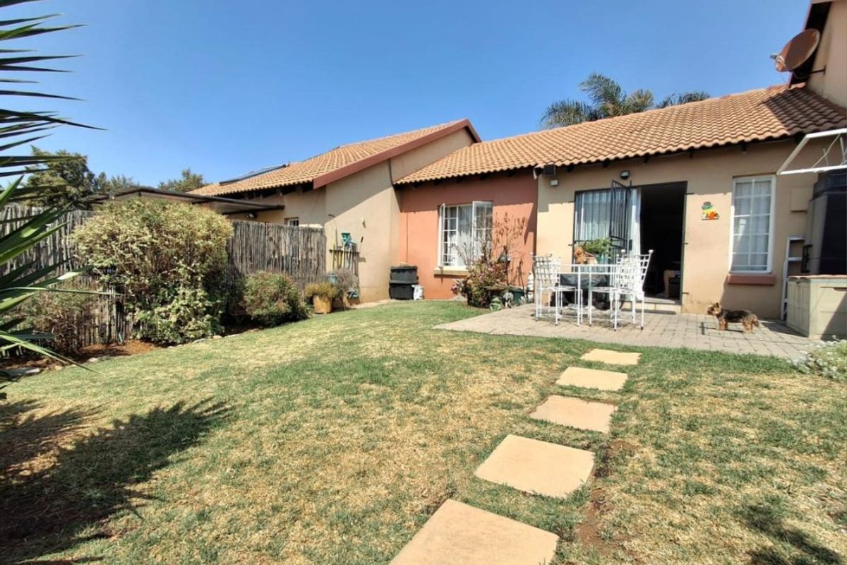 Rear view of the apartment featuring a private garden, paved patio area, and stepping stone path leading to the main entrance.