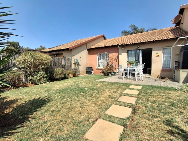 Rear view of the apartment featuring a private garden, paved patio area, and stepping stone path leading to the main entrance.