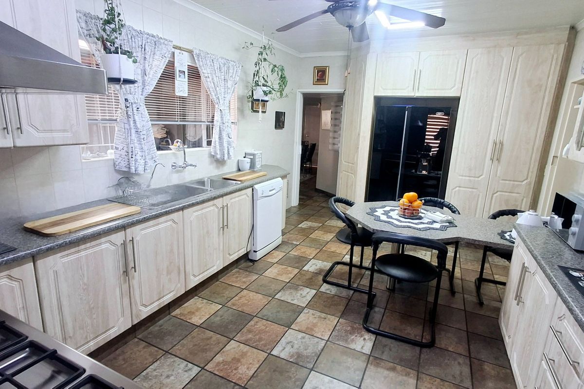 A functional kitchen featuring light-toned cabinetry, tiled flooring, a gas hob with extractor, and a dedicated breakfast nook area.