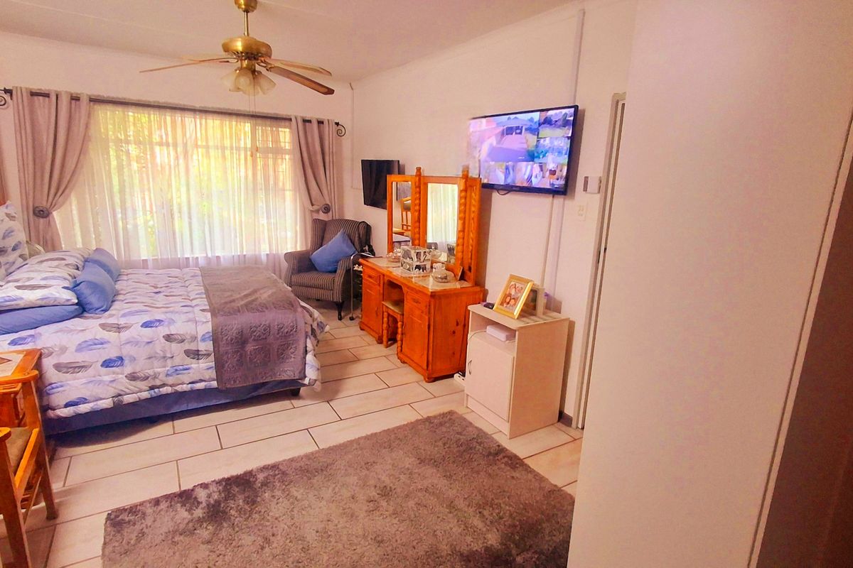 A spacious bedroom featuring tiled flooring, a ceiling fan, and built-in storage, offering a functional and comfortable living space.