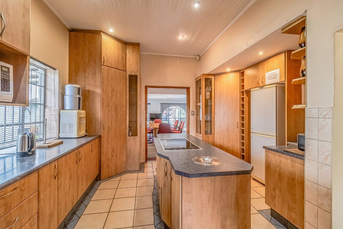 A functional kitchen featuring wooden cabinetry, a central island with a built-in hob, and tiled flooring, offering a practical layout for meal preparation.