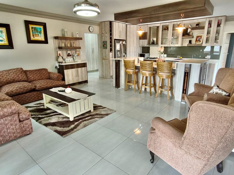 Spacious open-plan living area featuring a modern kitchen with a central island, tiled flooring, and integrated cabinetry, creating a functional and cohesive living space.