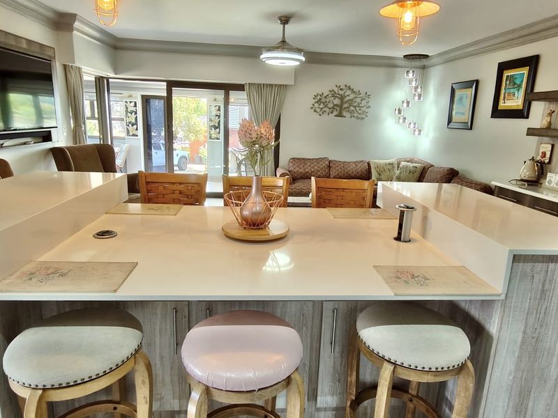 Spacious open-plan living area featuring a central kitchen island with quartz countertops, modern cabinetry, and seamless flow to the outdoor patio through sliding doors.