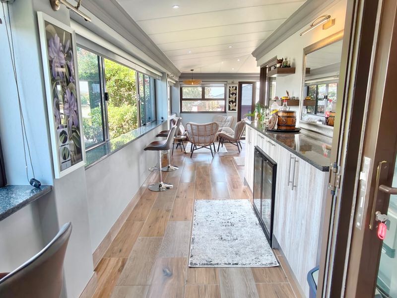 A bright, enclosed patio area featuring modern tiled flooring, granite-topped built-in cabinetry, and an integrated beverage fridge, perfect for entertaining.