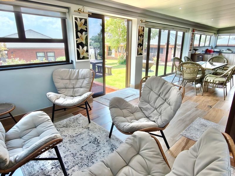 Bright open-plan living and dining area featuring laminate flooring, recessed lighting, and large sliding glass doors providing seamless access to the garden.