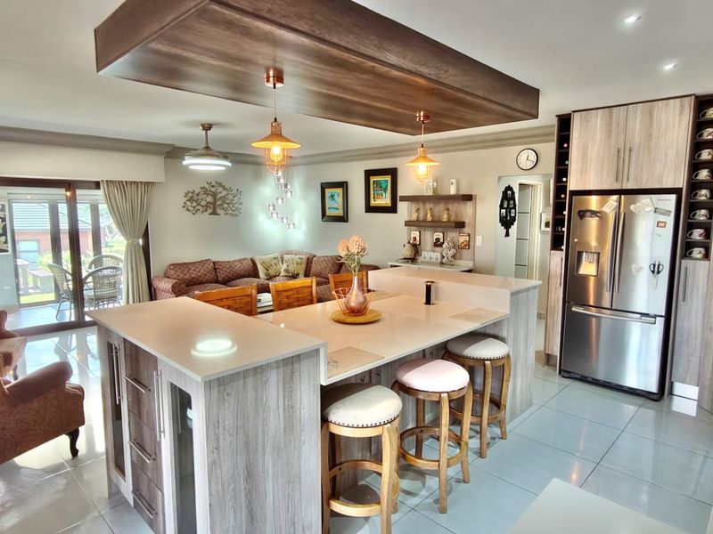 Spacious open-plan living area featuring a modern kitchen with a central island, quartz countertops, and seamless flow to the outdoor patio.