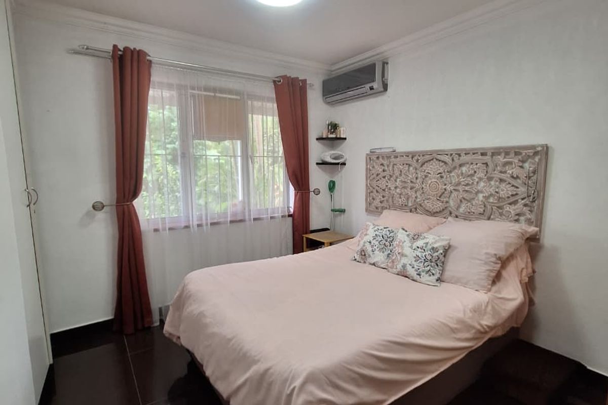 A bedroom featuring dark tiled flooring, built-in wardrobe, and a wall-mounted air conditioning unit.