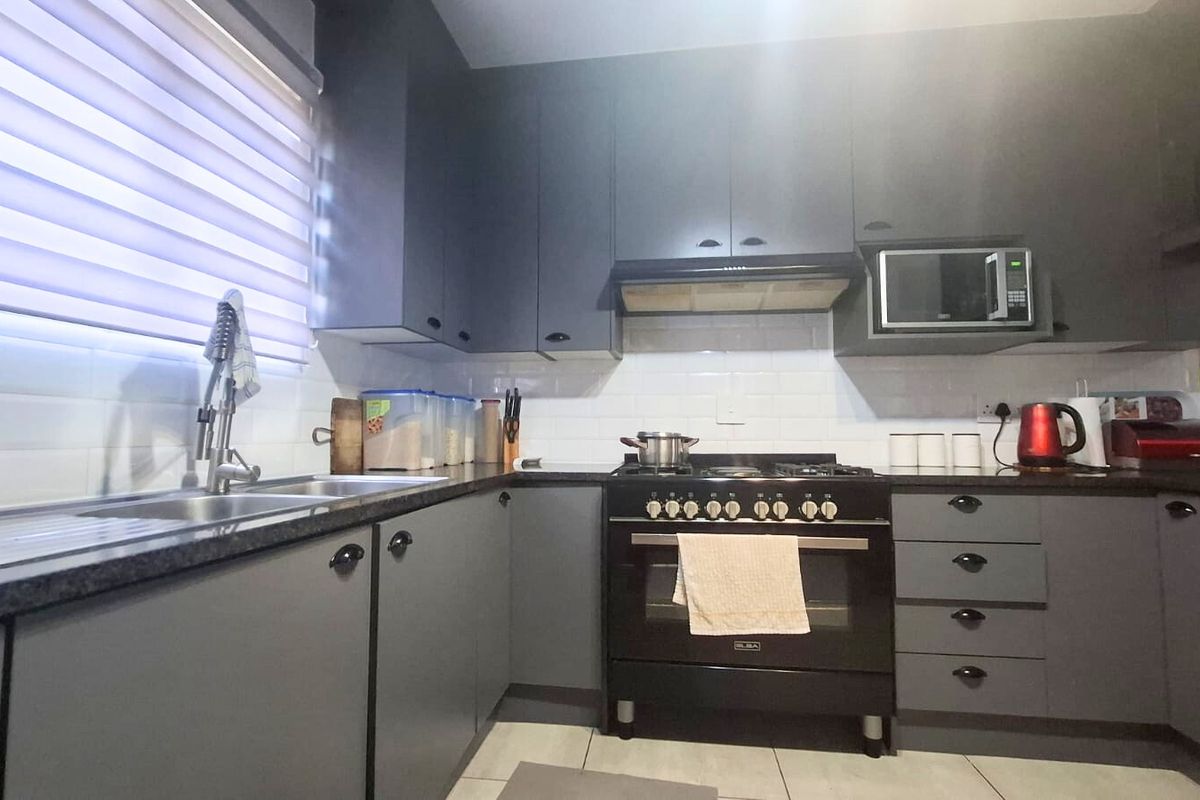 Modern kitchen featuring dark grey cabinetry, stone countertops, subway tile backsplash, and integrated appliances including a gas stove and oven.