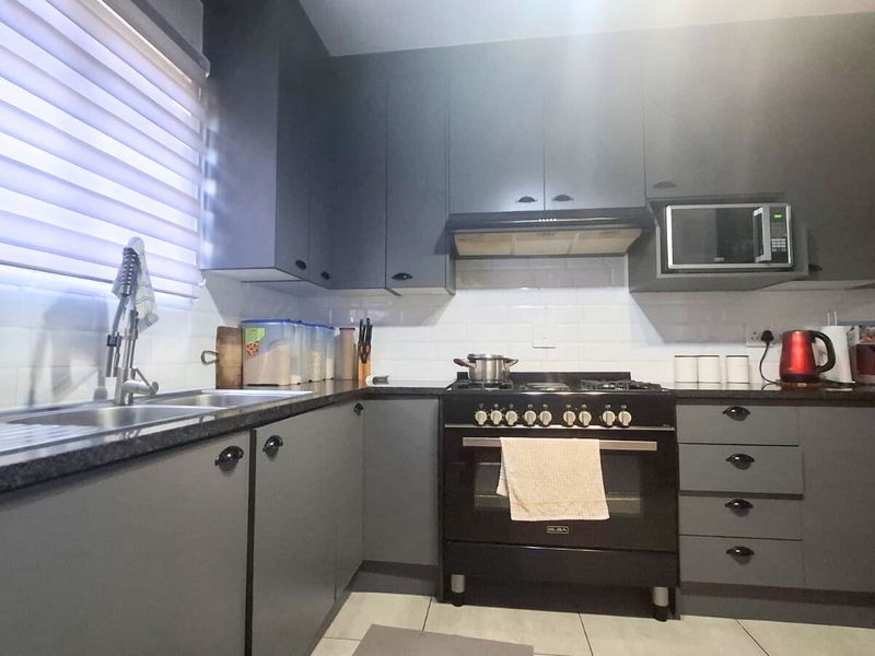 Modern kitchen featuring dark grey cabinetry, stone countertops, subway tile backsplash, and integrated appliances including a gas stove and oven.