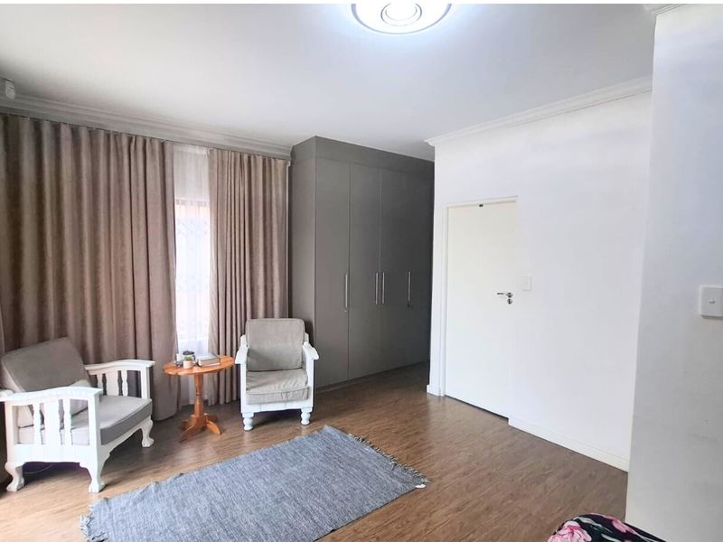 A well-maintained bedroom featuring laminate flooring, neutral walls, and ample built-in cupboard storage space.