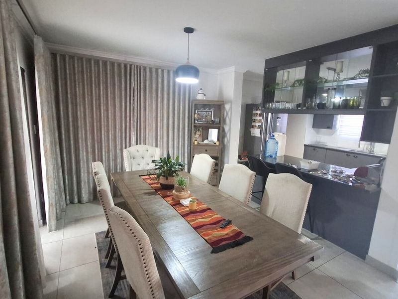 Open-plan dining area featuring tiled floors and a seamless transition to a modern kitchen with built-in cabinetry and a breakfast bar.