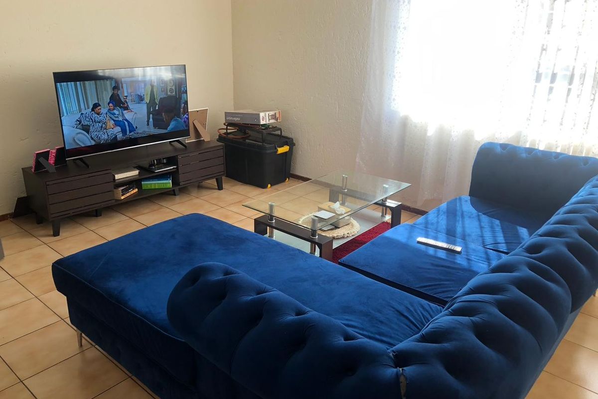 A living room featuring ceramic floor tiles and natural light from a window.