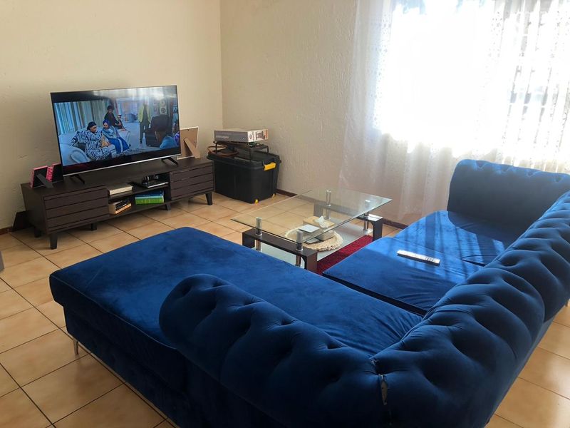 A living room featuring ceramic floor tiles and natural light from a window.
