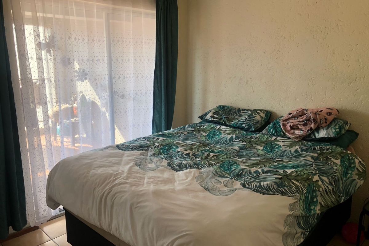 A bedroom featuring tiled flooring and a sliding glass door providing access to an outdoor area, with textured wall finishes.
