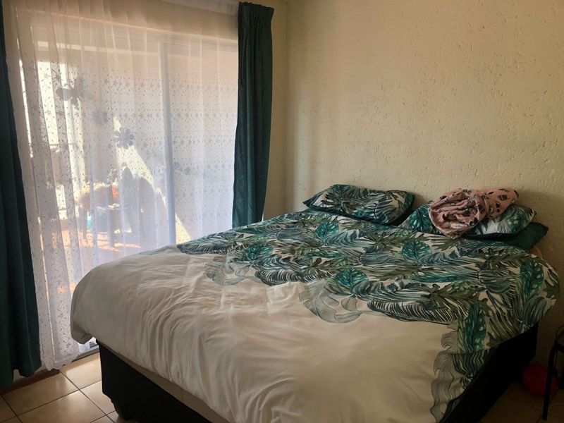 A bedroom featuring tiled flooring and a sliding glass door providing access to an outdoor area, with textured wall finishes.